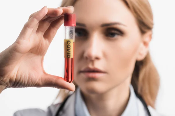 Nurse holding test tube with covid lettering on blurred foreground isolated on white — Stock Photo