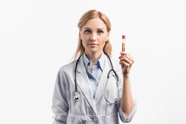 Enfermera en bata blanca sosteniendo tubo de ensayo con letras covid y mirando a la cámara aislada en blanco - foto de stock