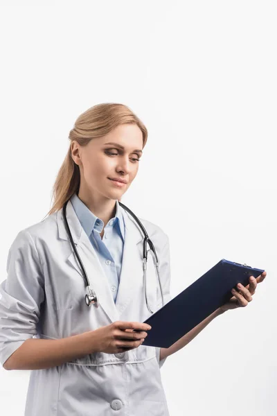 Nurse in white coat looking at clipboard isolated on white — Stock Photo