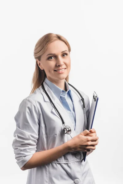 Happy nurse in white coat holding clipboard isolated on white — Stock Photo