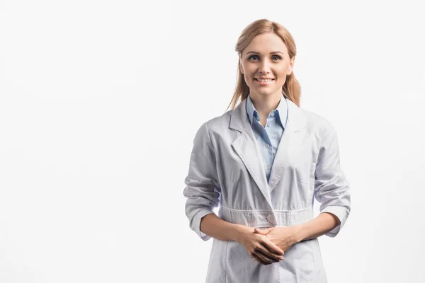 Enfermera feliz en bata blanca de pie con las manos apretadas aisladas en blanco - foto de stock