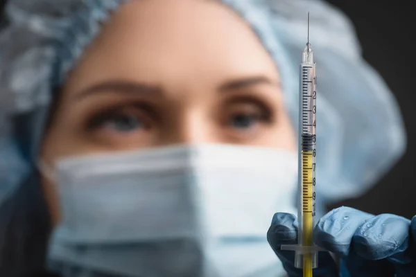 Syringe with vaccine near nurse in medical cap on blurred background — Stock Photo