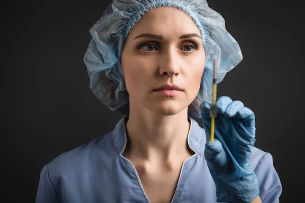 Syringe with vaccine in hand of nurse in latex glove on blurred background isolated on dark grey — Stock Photo