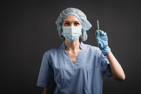 Infermiere in maschera medica e siringa con cappuccio contenente vaccino isolato su grigio scuro — Foto stock