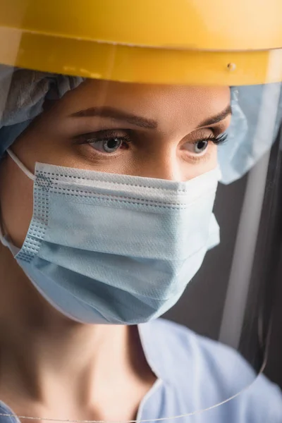 Медсестра в медицинской маске и щиты для лица изолированы на темно-сером — стоковое фото