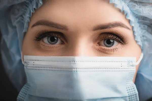 Nahaufnahme einer Krankenschwester in medizinischer Mütze und Maske, die in die Kamera blickt — Stockfoto