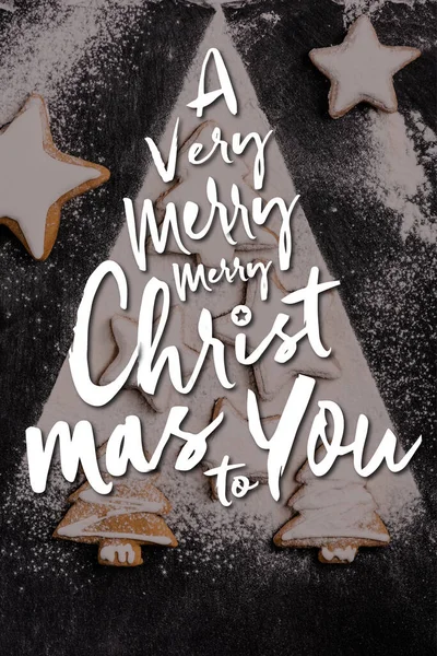 Vista superior de las galletas de pan de jengibre de Navidad cubiertas con azúcar en polvo cerca de una muy feliz Navidad para que las letras - foto de stock