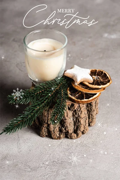 Bougie parfumée avec brunch de pin, tranches d'orange séchées et biscuit sur support en bois près de joyeux lettrage de Noël — Photo de stock