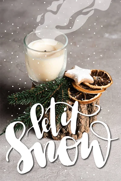 Vela perfumada con brunch de pino, rodajas de naranja secas y galleta en soporte de madera cerca de dejar es letras de nieve - foto de stock
