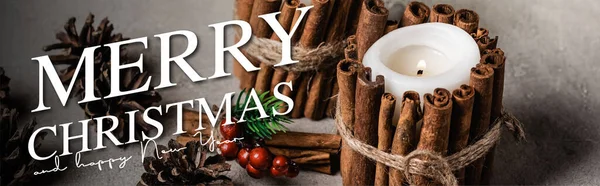 Bougies décorées avec des bâtons de cannelle près de cônes de pin et joyeux Noël et heureux nouveau lettrage de l'année, bannière — Photo de stock