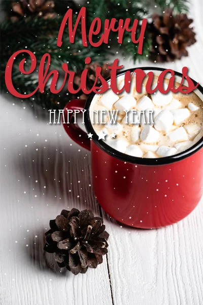 Rote Tasse Kakao in der Nähe von Tannenzapfen und frohe Weihnachten, frohes neues Jahr Schriftzug auf verschwommenem Holzgrund — Stockfoto