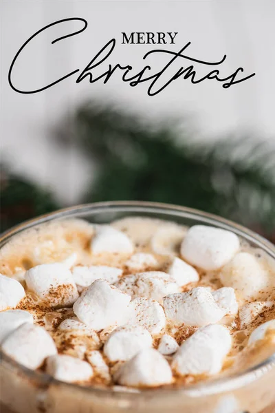 Close up view of glass cup of cocoa with marshmallows and cinnamon near merry christmas lettering — Stock Photo