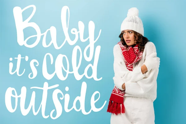 Freezing young woman in winter outfit embracing herself near baby its cold outside lettering on blue — Stock Photo