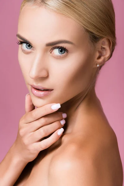 Красива блондинка з ідеальною шкірою, що торкається обличчя ізольована на рожевому — стокове фото