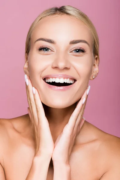 Smiling beautiful blonde woman touching face isolated on pink — Stock Photo