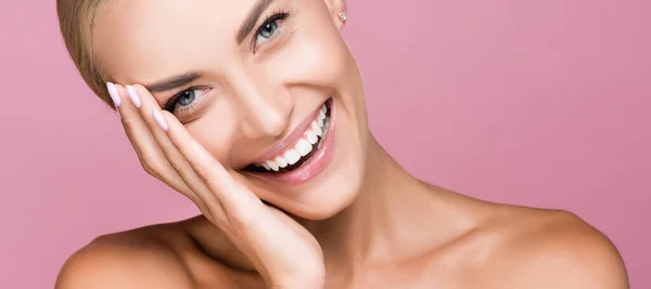 Bella donna bionda sorridente che tocca il viso isolato sul rosa, striscione — Foto stock