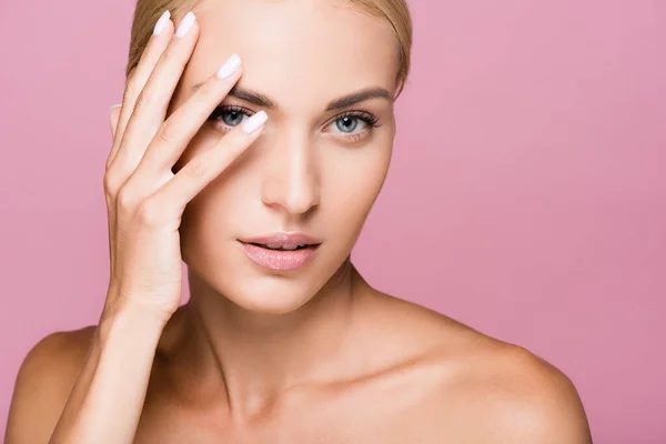 Beautiful blonde woman posing with hand on face isolated on pink — Stock Photo