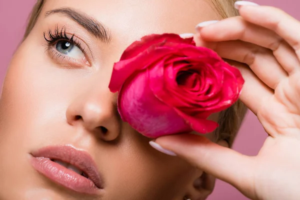 Bela mulher loira com flor de rosa no olho isolado em rosa — Fotografia de Stock