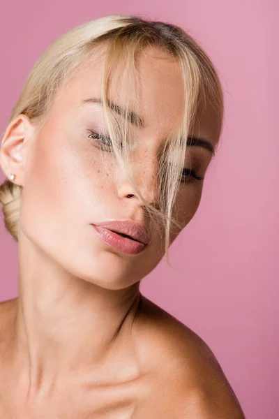 Bella donna bionda con lentiggini che soffia sui capelli isolati su rosa — Foto stock
