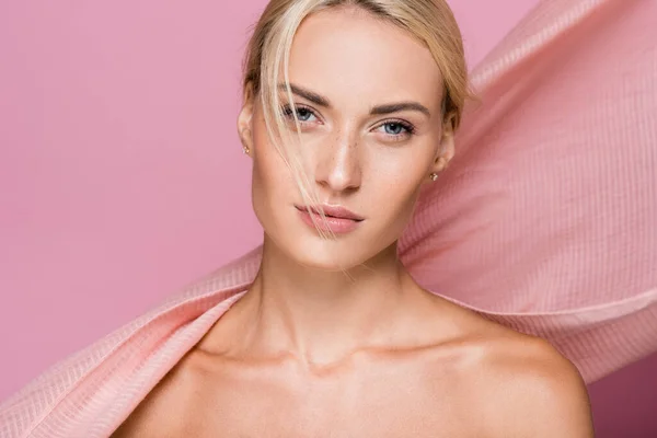 Hermosa mujer rubia con pecas y hombros desnudos cerca de la cortina aislada en rosa - foto de stock