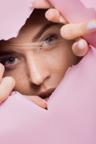 Mulher bonita com sardas no buraco de papel rosa — Fotografia de Stock