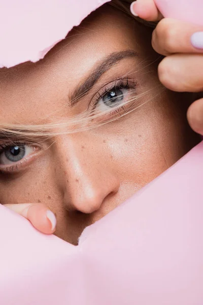 Beautiful woman with freckles in pink paper hole — Stock Photo