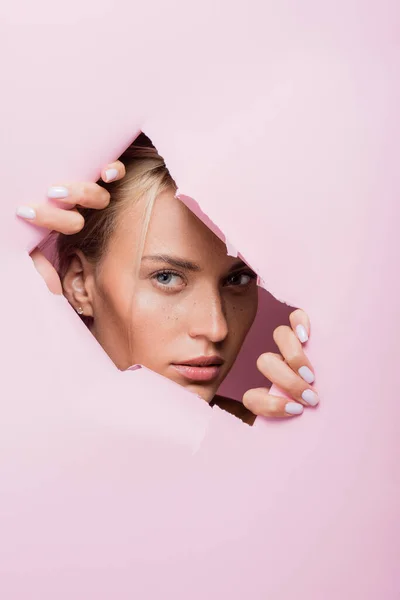 Schöne Frau mit Sommersprossen in rosa Papierloch — Stockfoto