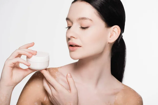 Jeune belle femme avec vitiligo tenant crème cosmétique isolé sur blanc — Photo de stock