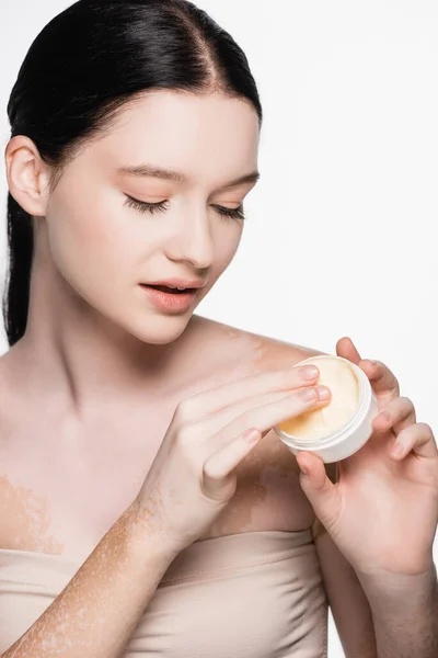 Young beautiful woman with vitiligo applying cosmetic cream isolated on white — Stock Photo