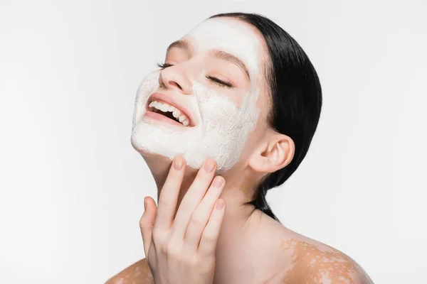 Lächelnde junge schöne Frau mit Vitiligo und Tonmaske auf dem Gesicht isoliert auf weiß — Stockfoto