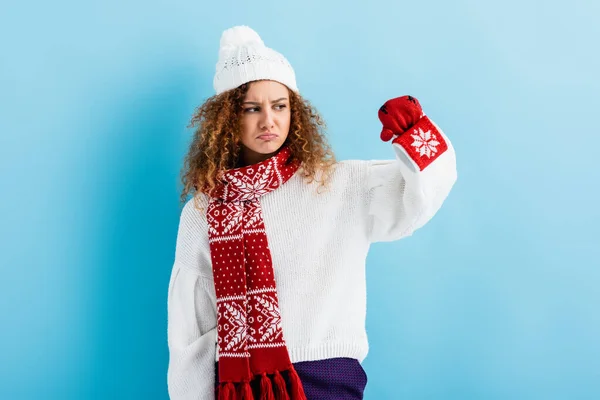 Traurige Frau in Hut und Pullover mit leerer Tasse im Strickhalter auf blau — Stockfoto