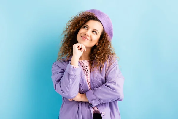 Mulher sonhadora na boina olhando para longe e sorrindo no azul — Fotografia de Stock