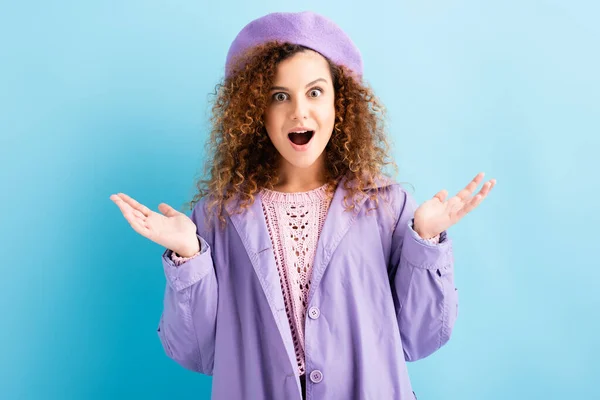 Amazed young woman with open mouth gesturing on blue — Stock Photo