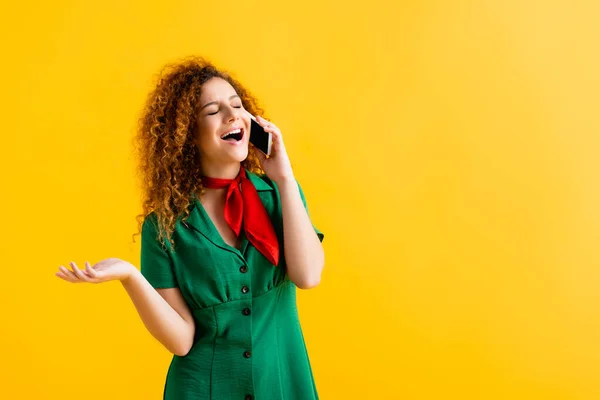 Verblüffte junge Frau spricht auf Smartphone isoliert auf gelb — Stockfoto