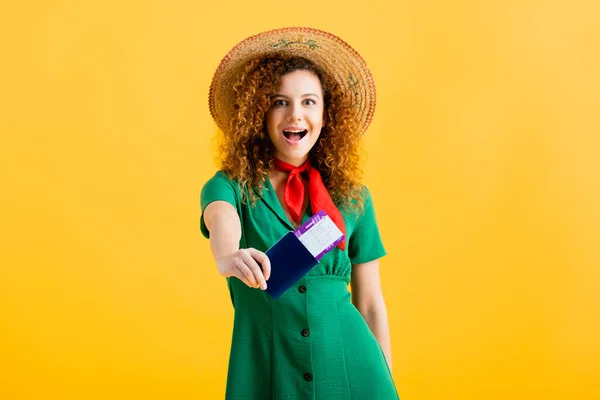 Femme étonnée en chapeau de paille tenant passeport avec billet de rame isolé sur jaune — Photo de stock