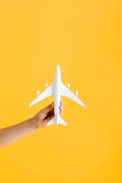 Vista recortada de mujer sosteniendo juguete avión aislado en amarillo - foto de stock