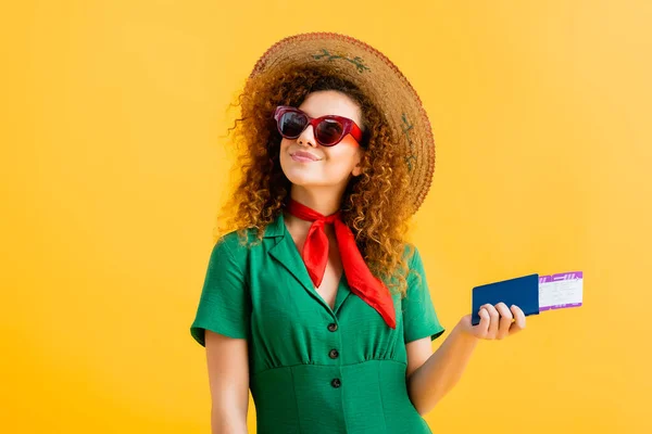 Donna allegra in cappello di paglia, occhiali da sole e vestito con passaporto su giallo — Foto stock