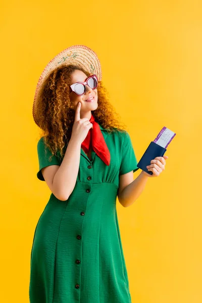 Joyful woman in straw hat, sunglasses and dress holding passport on yellow — Stock Photo