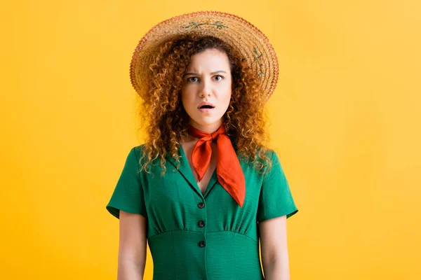Sorpresa giovane donna in cappello di paglia e vestito verde urlando sul giallo — Foto stock
