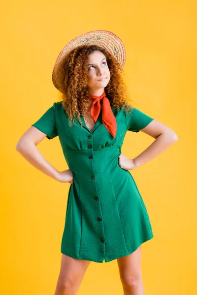 Mulher descontente em chapéu de palha e vestido verde de pé com as mãos em quadris em amarelo — Fotografia de Stock