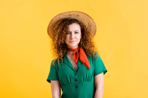 Young woman in green dress and straw hat looking at camera on yellow — Stock Photo