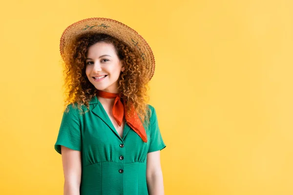 Sorrindo jovem mulher em vestido verde e chapéu de palha olhando para a câmera isolada no amarelo — Fotografia de Stock