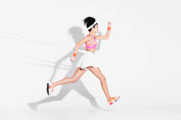 Vue latérale de la sportive faisant de l'exercice avec bande de résistance sur blanc — Photo de stock