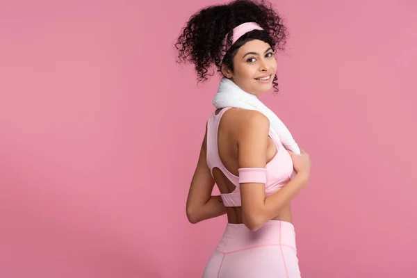 Curly sportswoman with towel on shoulders smiling isolated on pink — Stock Photo