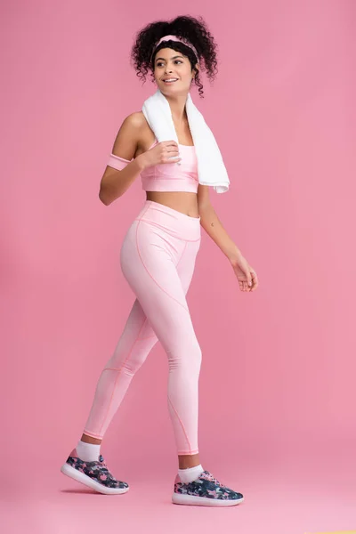 Fröhliche junge Sportlerin mit Handtuch auf den Schultern, die auf rosa — Stockfoto