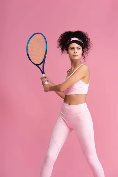 Jovem esportiva segurando raquete de tênis isolado em rosa — Fotografia de Stock