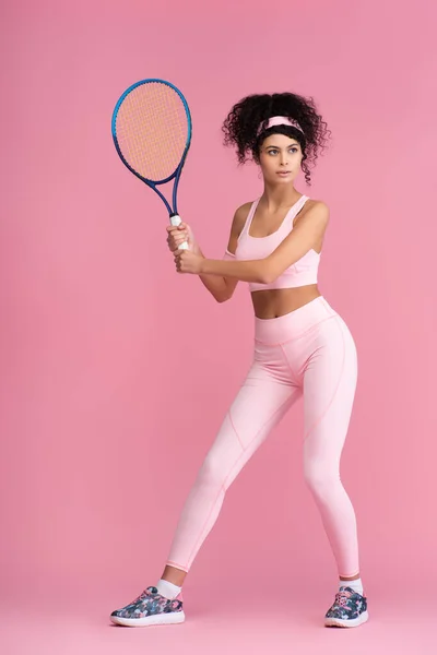 Volle Länge der sportlichen jungen Frau mit Tennisschläger auf rosa — Stockfoto