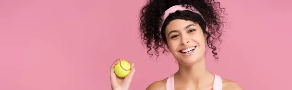 Joyeuse jeune femme tenant une balle de tennis isolée sur rose, bannière — Photo de stock