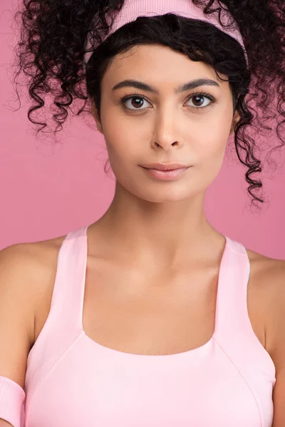 Young and curly sportswoman in headband looking at camera isolated on pink — Stock Photo