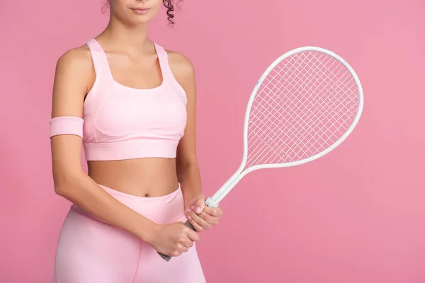 Partial view of young woman in sportswear holding tennis racket isolated on pink — Stock Photo